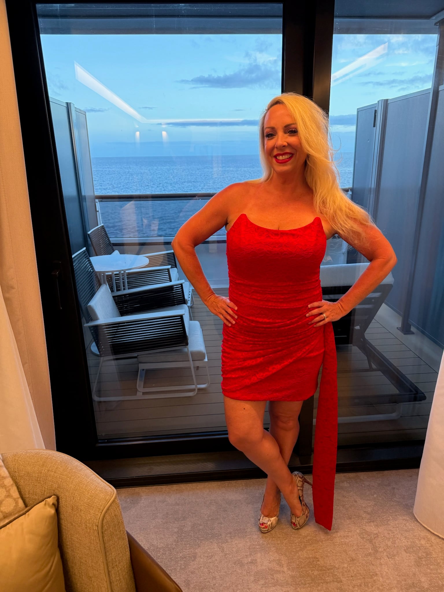 Aimee Byrd in red cocktail dress on Deck 6 terrace at sunset