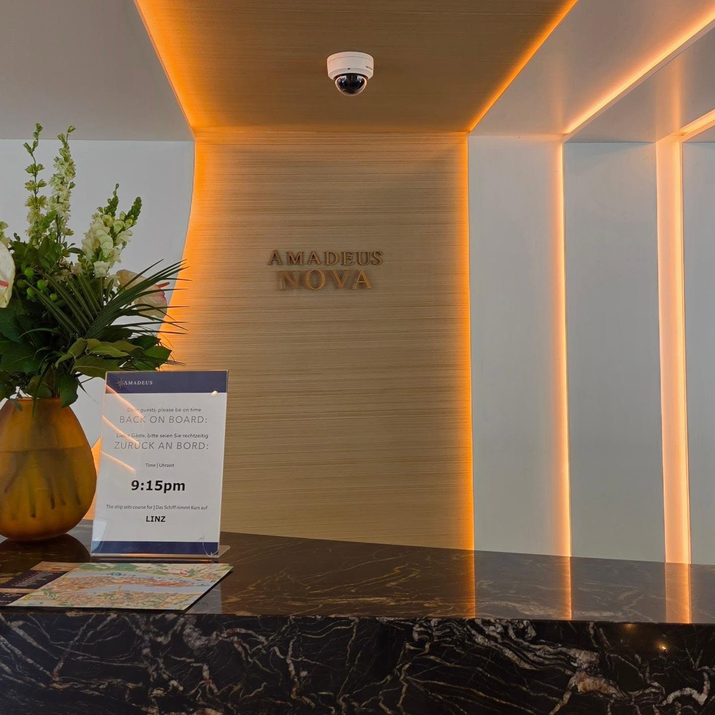 Amadeus Nova reception desk and golden illuminated lobby with Linz Danube port schedule