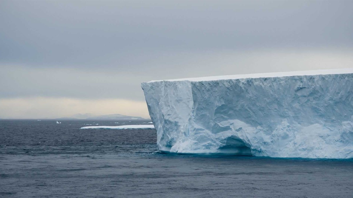 The National Geographic Quest expedition ship sailing through calm Alaskan waters with a glacier and mountains in the background, showcasing its nimble design
