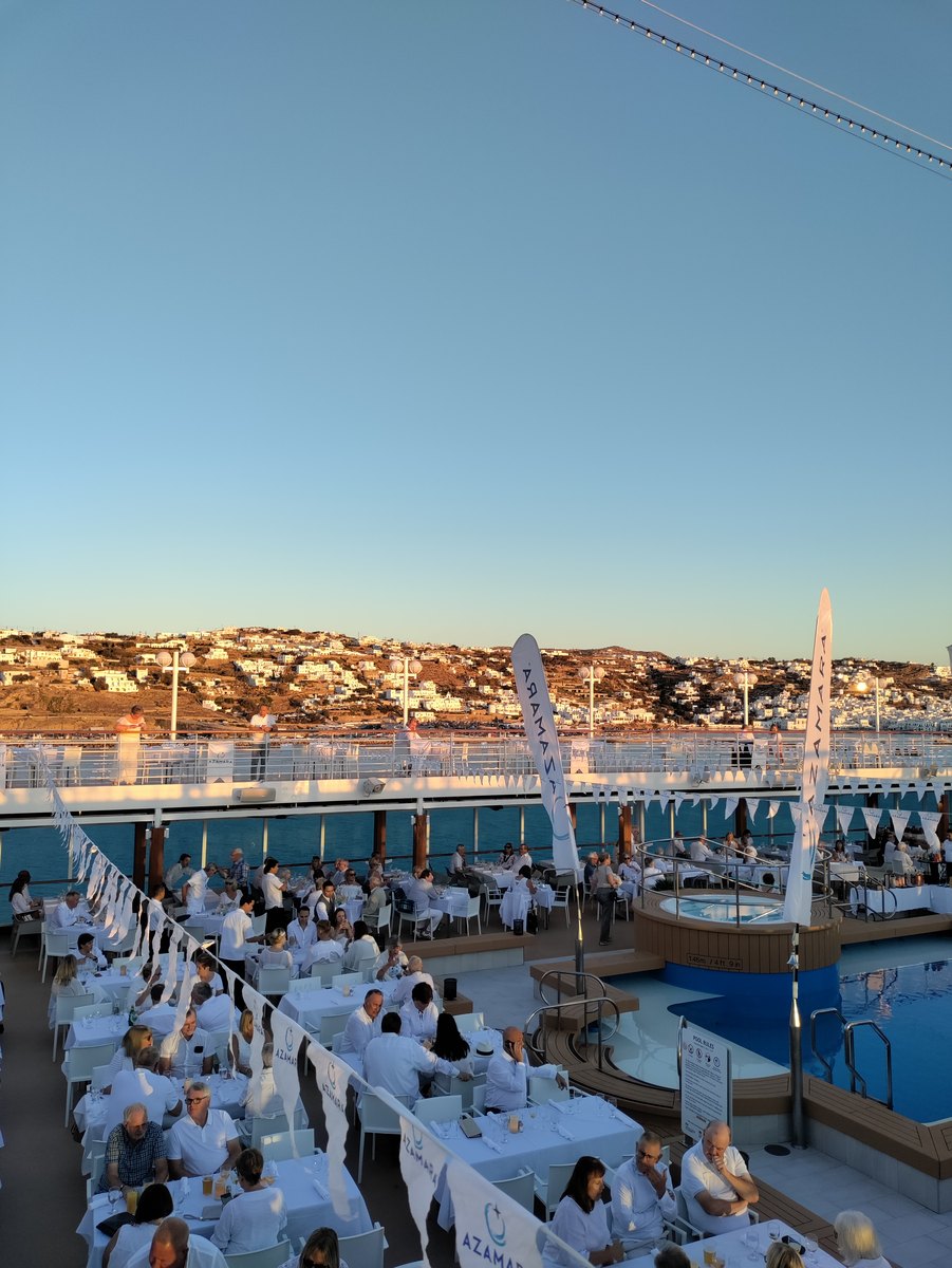 Guests and ship officers dressed in white dancing on the open deck under the stars