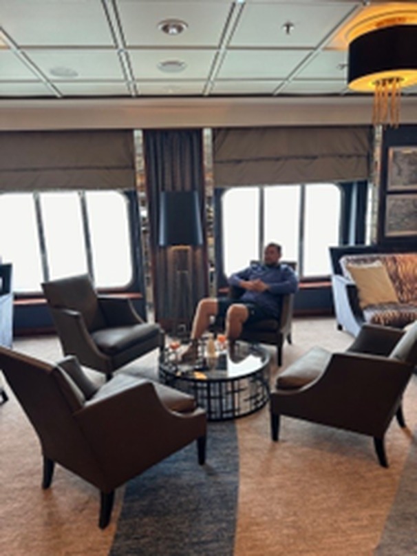 Relaxing in the plush seating of the Crystal Cove lounge aboard Crystal Symphony with panoramic ocean view windows