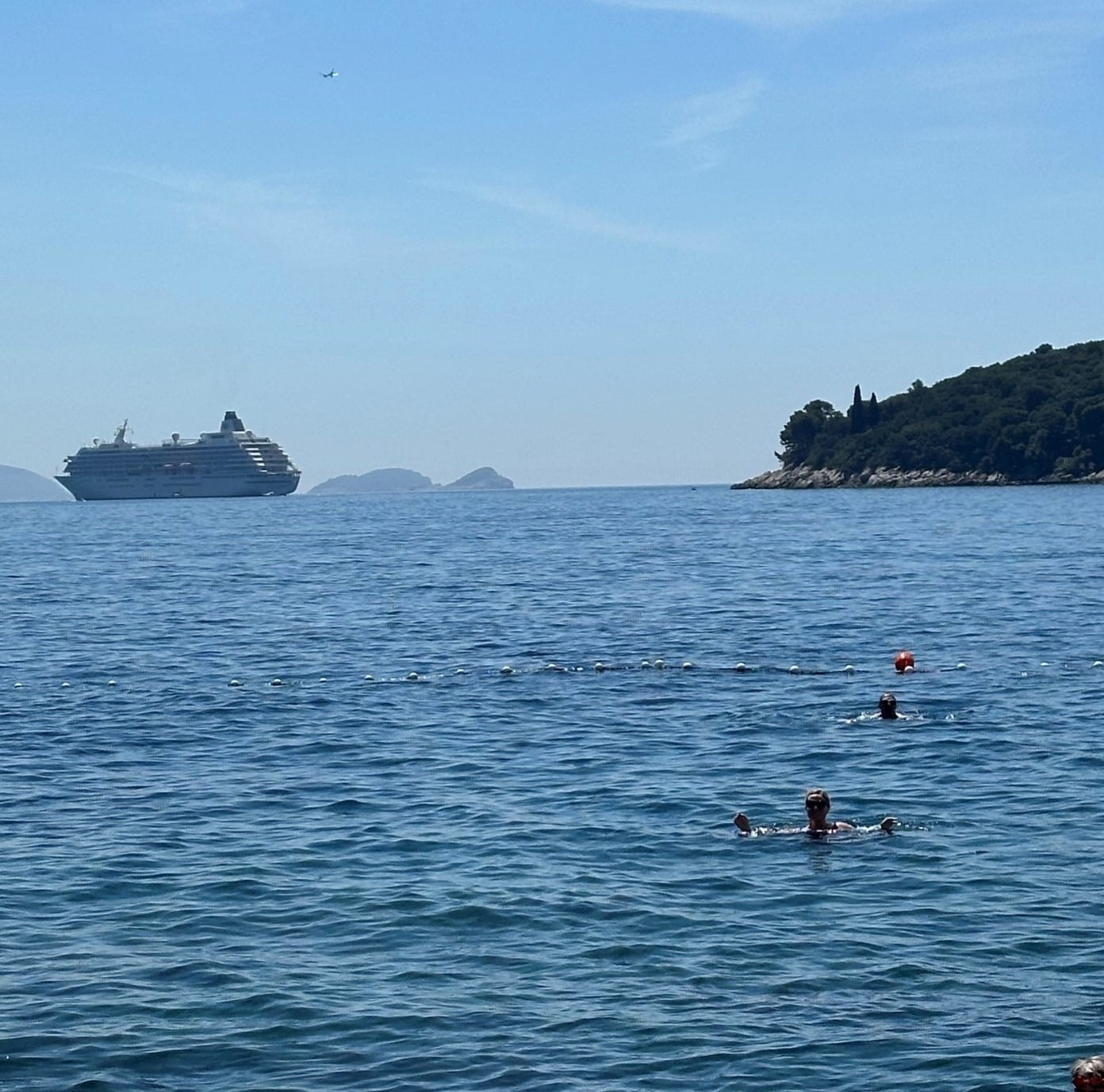 Crystal Symphony anchored in the sparkling blue waters of the Mediterranean with swimmers in the foreground