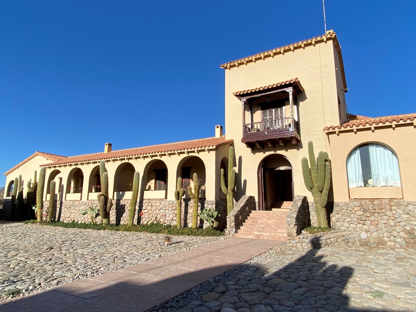 Historic white adobe facade of Estancia Colome set against mountain vineyards