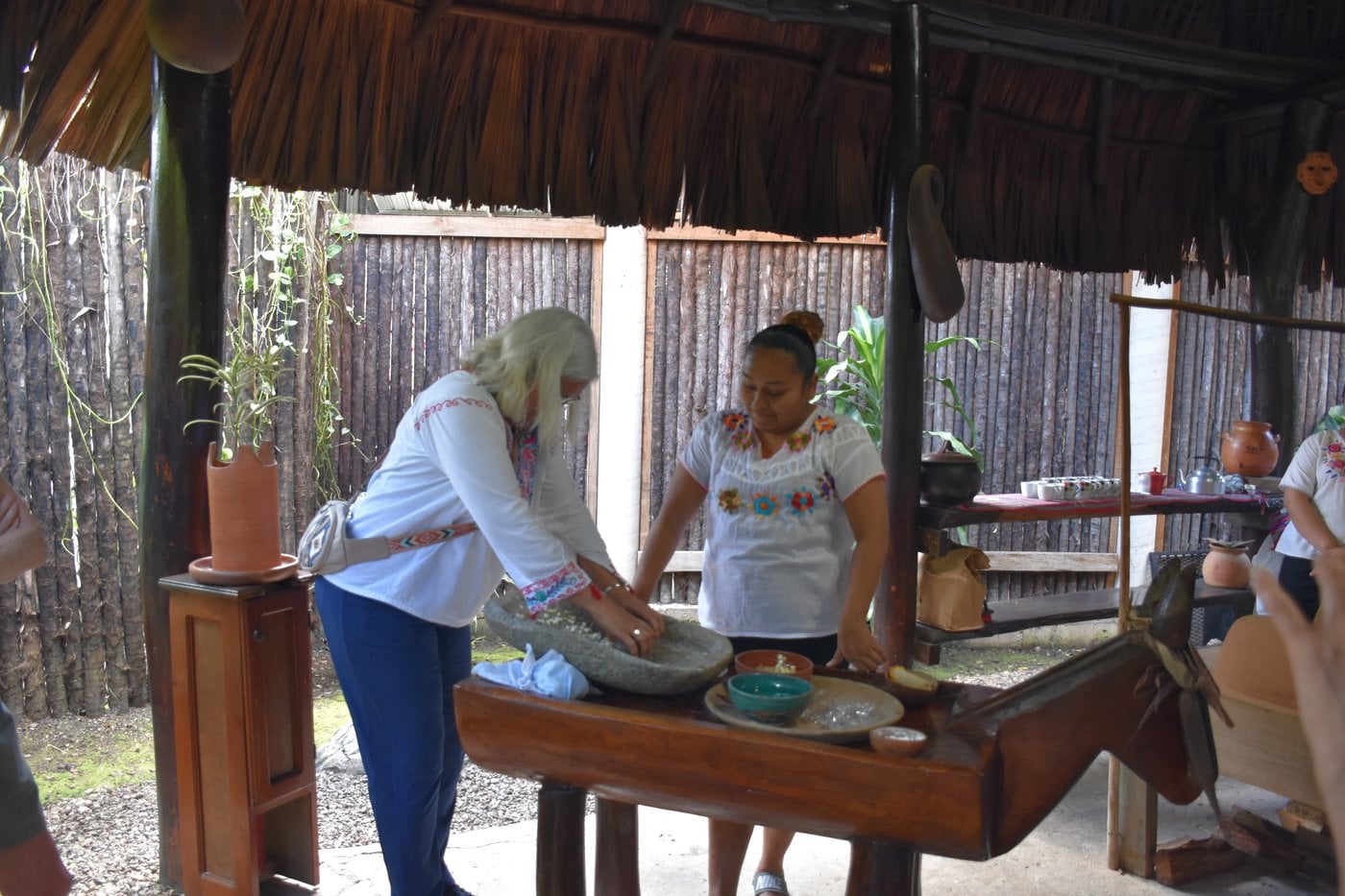 Grinding corn dough on volcanic stone metate y mano to make fresh tortillas