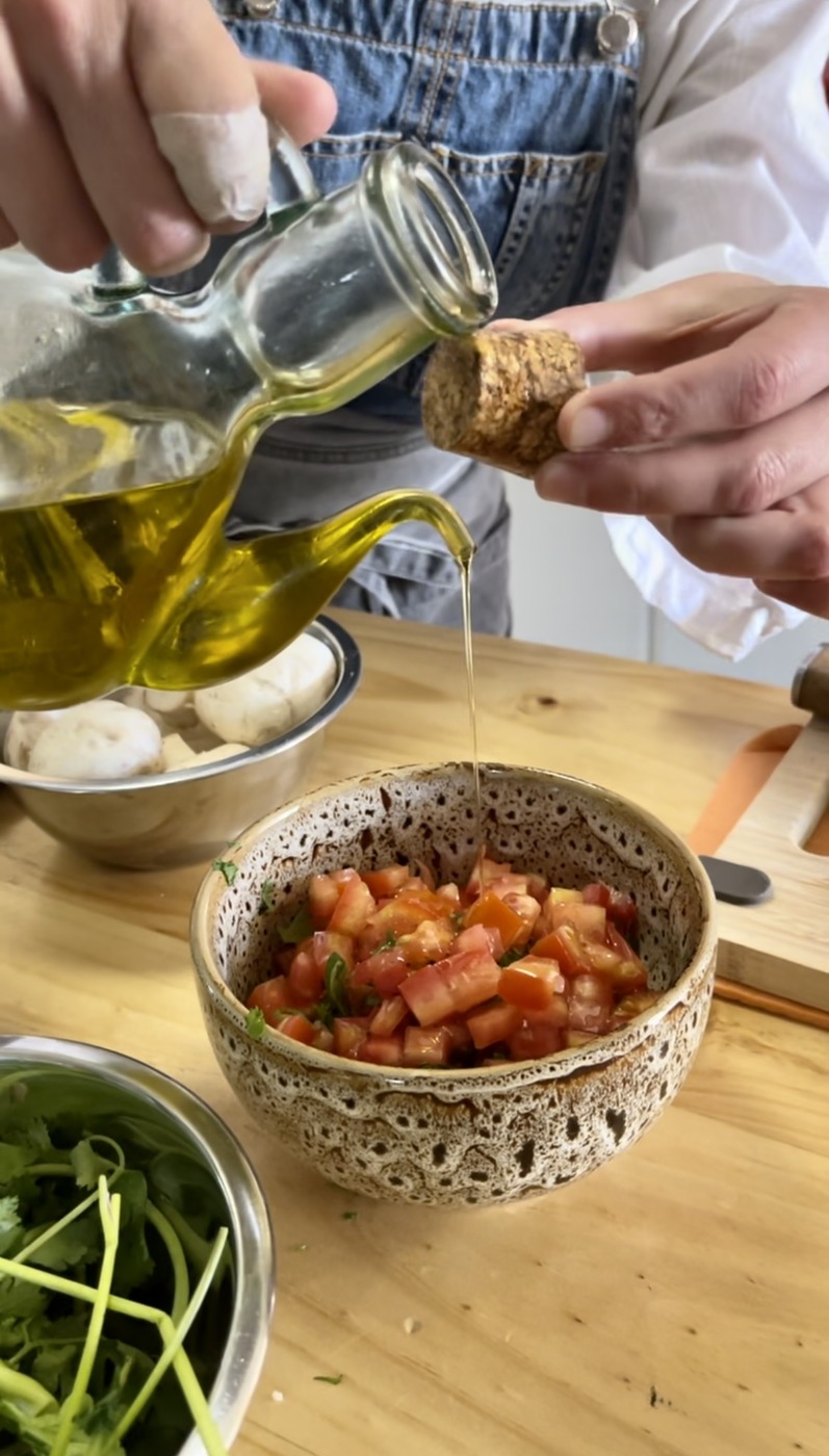 Drizzling olive oil into a bowl of fresh traditional Chilean pebre salsa