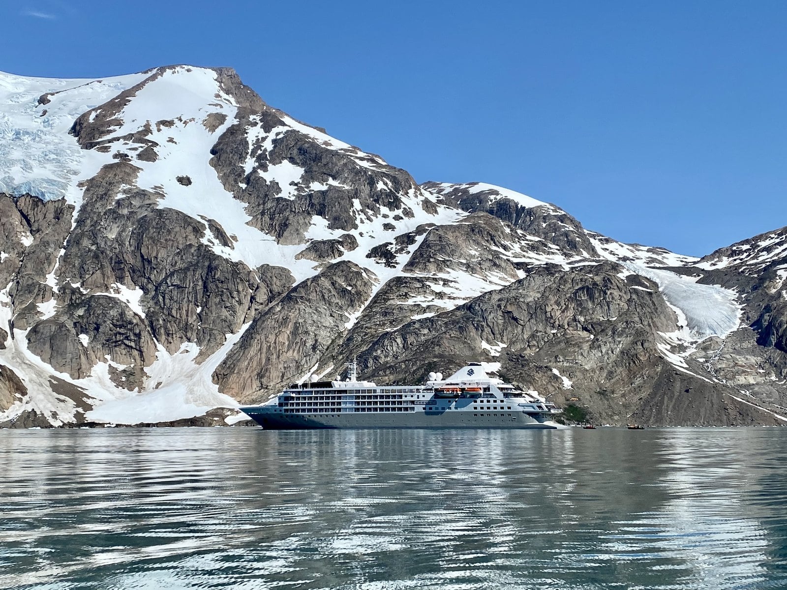 Silversea Silver Wind anchored in an Arctic Greenland fjord flanked by snow-capped mountains