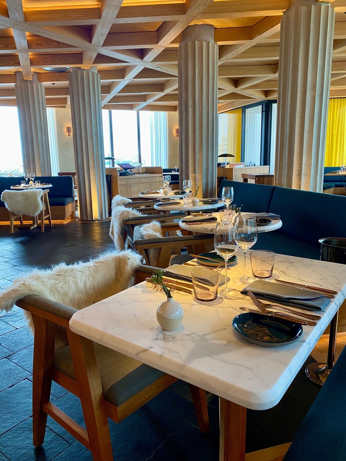 TIDES Restaurant interior at The Reykjavik EDITION featuring custom wood columns, sculptural lighting, and fine dining tables