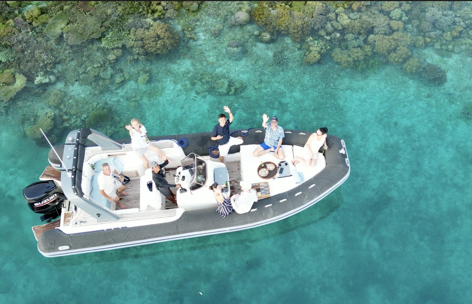 Aerial drone view of Aqua Blu luxury tender boat cruising over pristine turquoise coral reef in Raja Ampat, Indonesia