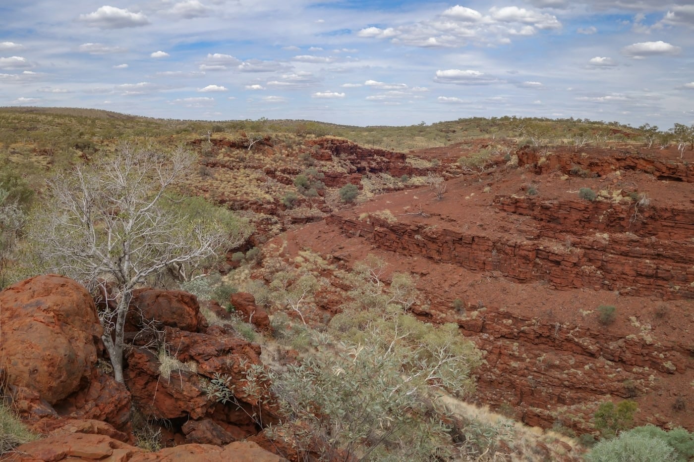 Expedition Zodiac cruising beneath sheer red rock cliffs along the Kimberley coast