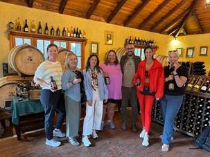 Travel advisors gathered around oak barrels in a rustic Madeiran cider cellar during an artisan tasting