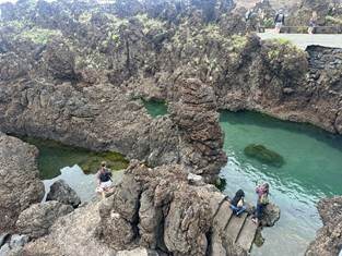 Natural volcanic black lava rock pools filled with crystalline turquoise seawater at Porto Moniz in Madeira