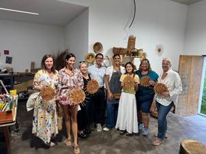 Travel advisors holding handcrafted wicker works alongside a master Madeiran artisan in her workshop