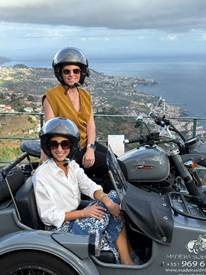 Travel advisors wearing helmets and goggles enjoying a vintage motorcycle sidecar tour overlooking Funchal coast