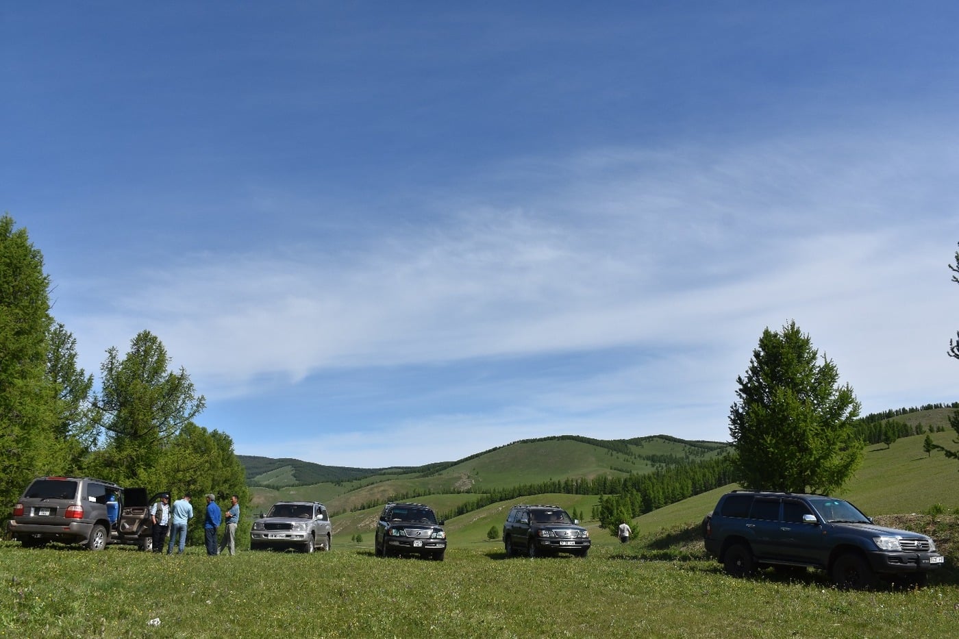G Adventures 4x4 convoy vehicles and drivers resting during an overland steppe lunch stop