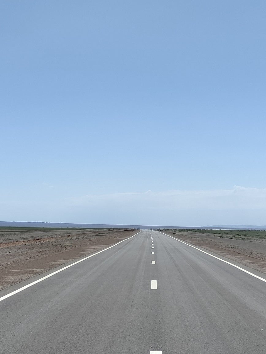 Smooth paved highway stretching across the vast open Mongolian steppe