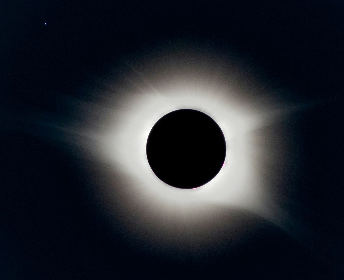 Spectacular view of total solar eclipse corona glowing in the dark daytime sky