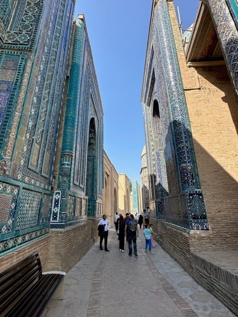 Narrow medieval walkway framed by turquoise tiled mausoleums in Shah-i Zinda