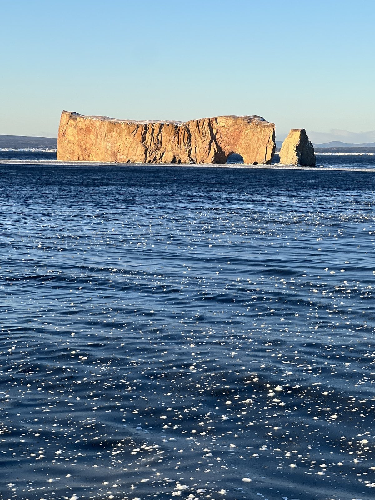 Iconic Perce Rock surrounded by winter sea ice in the Gulf of St. Lawrence Gaspe