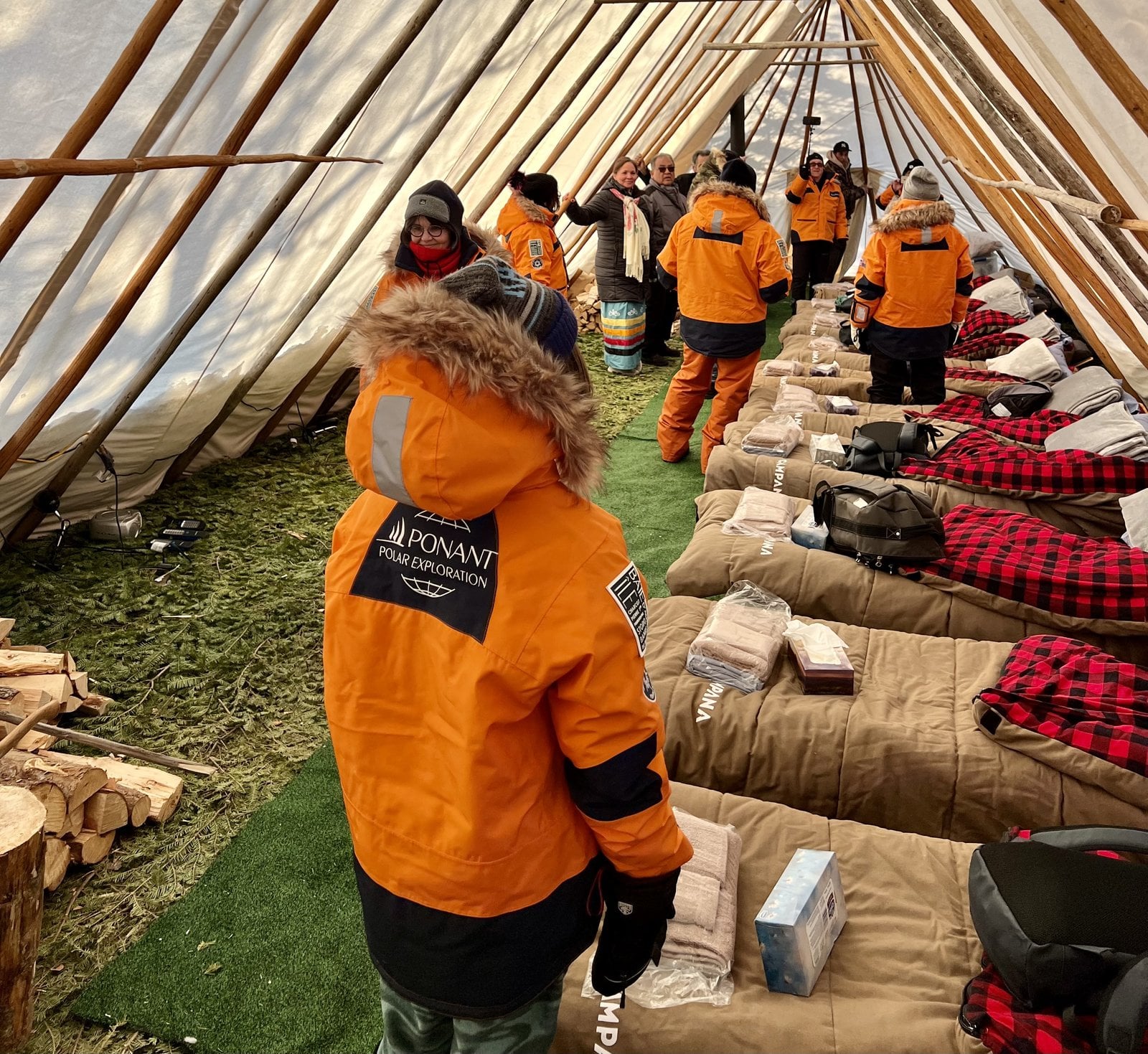 Ponant expedition guests inside traditional Innu shaputuan tent at Mani-Utenam