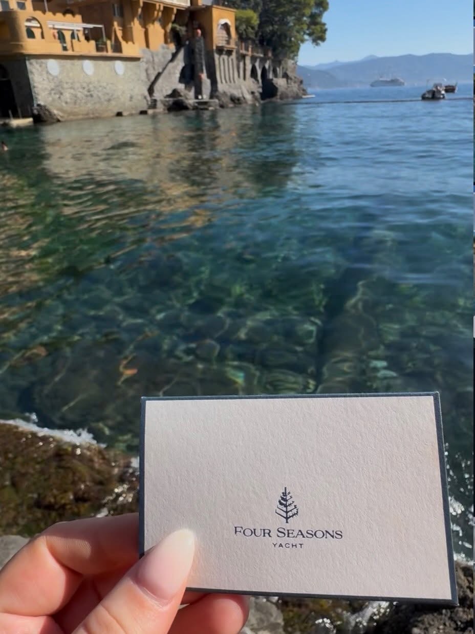 Aimee Byrd holding Four Seasons Yacht keycard over crystal clear Mediterranean water