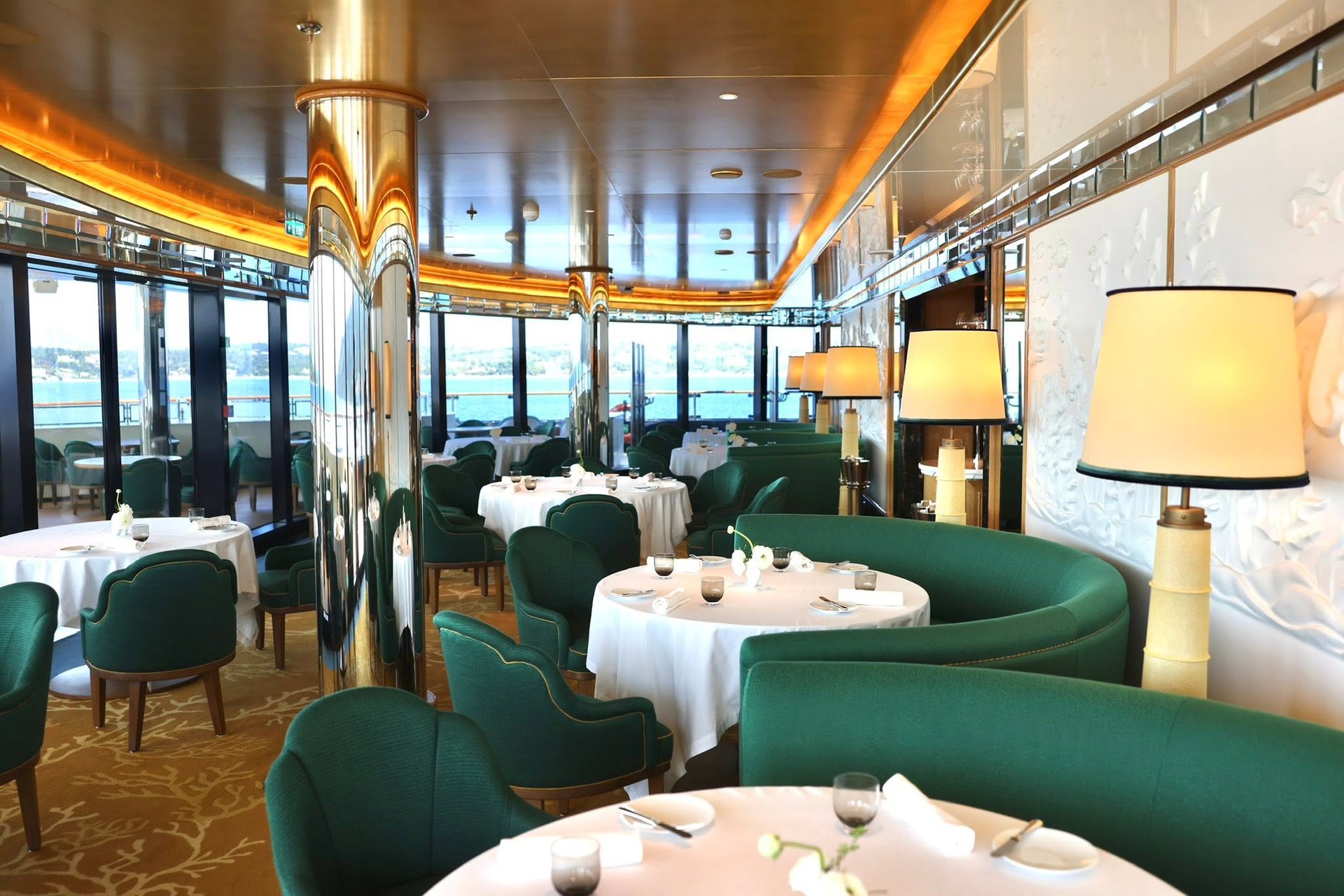 Signature fine dining restaurant with curved green velvet booths and ocean views on Four Seasons Yachts