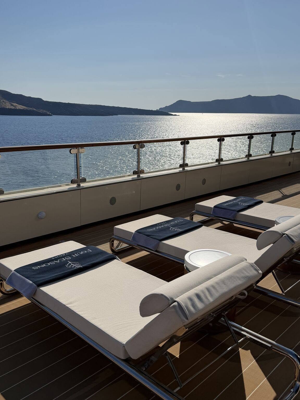 Plush sun loungers on teak promenade deck overlooking the ocean on Four Seasons Yachts