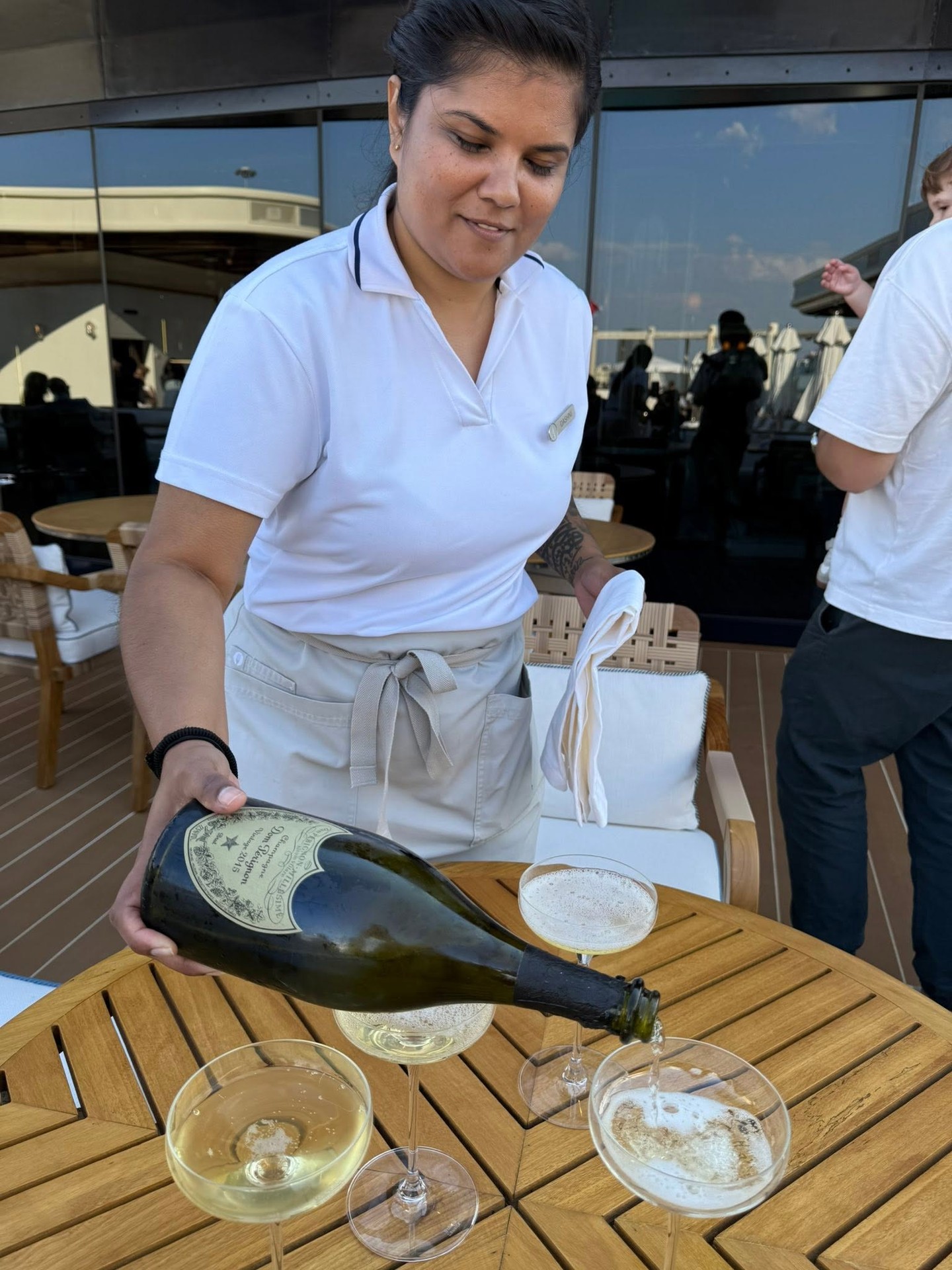 Attendant pouring vintage champagne on private suite terrace aboard Four Seasons Yachts