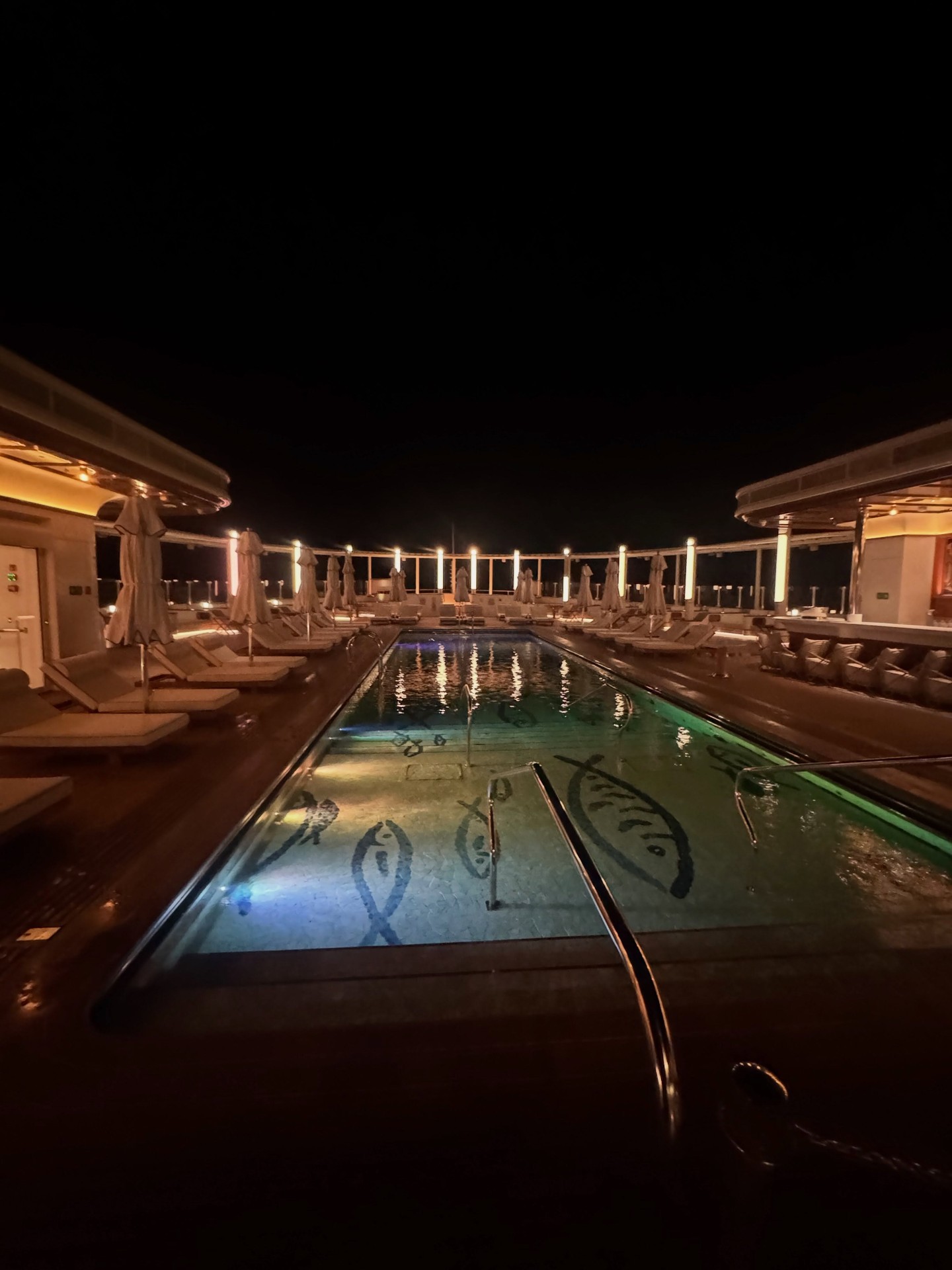 The 20-meter pool deck illuminated dramatically at night on Four Seasons Yachts