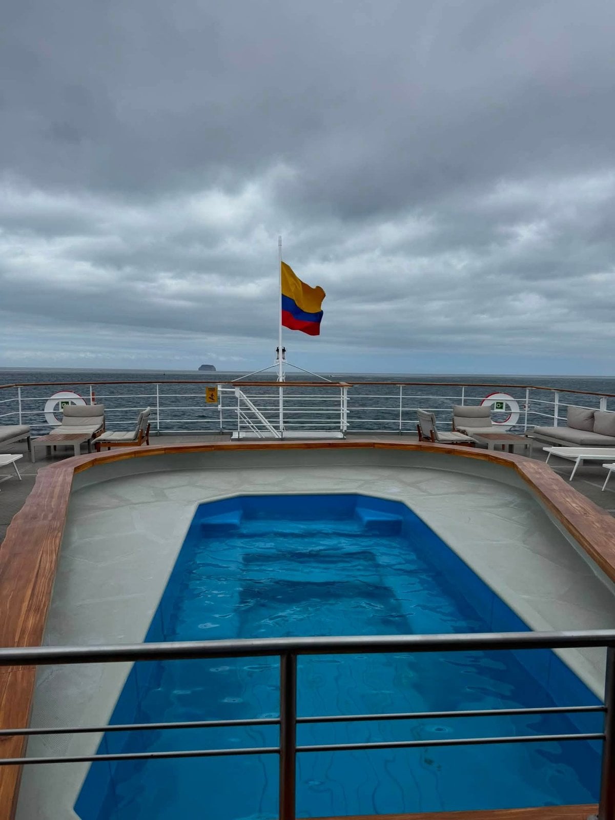 The open-air aft swimming pool deck flying the Ecuadorian flag aboard the MV Galapagos Legend