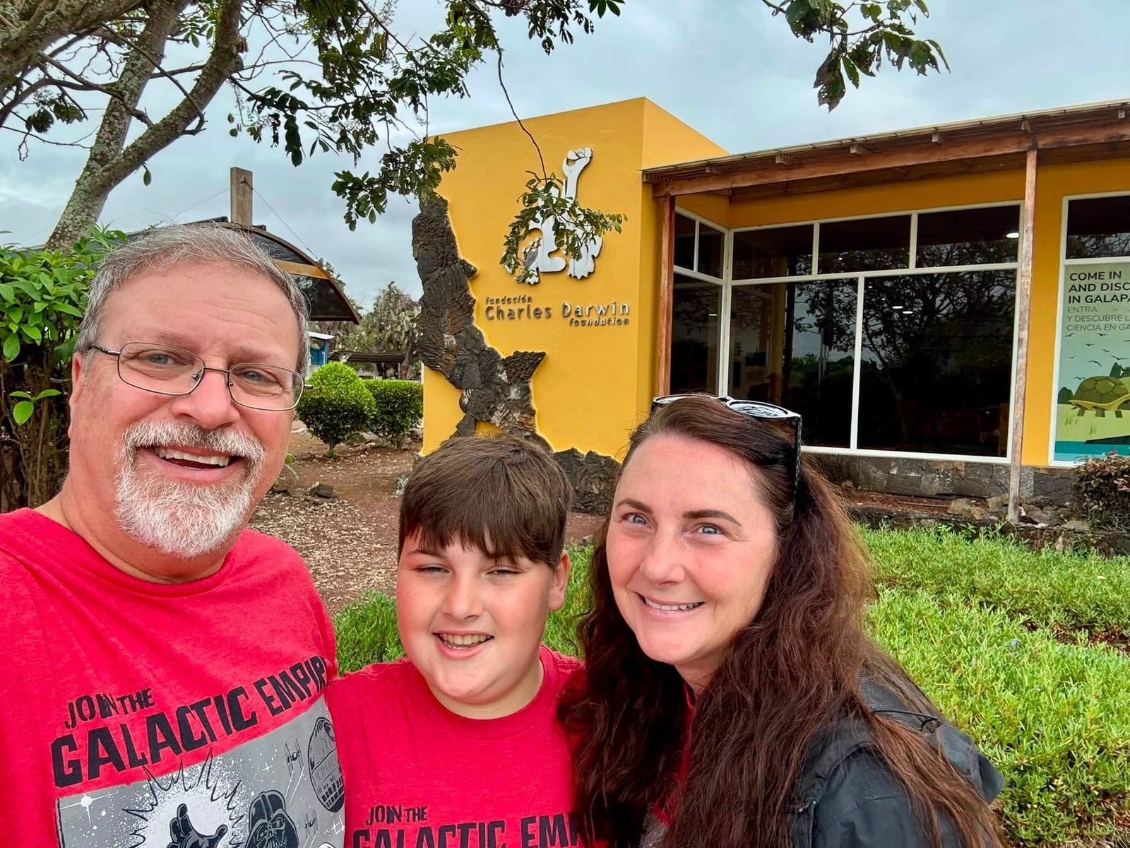 The Herring family smiling in front of the Charles Darwin Research Station on Santa Cruz Island