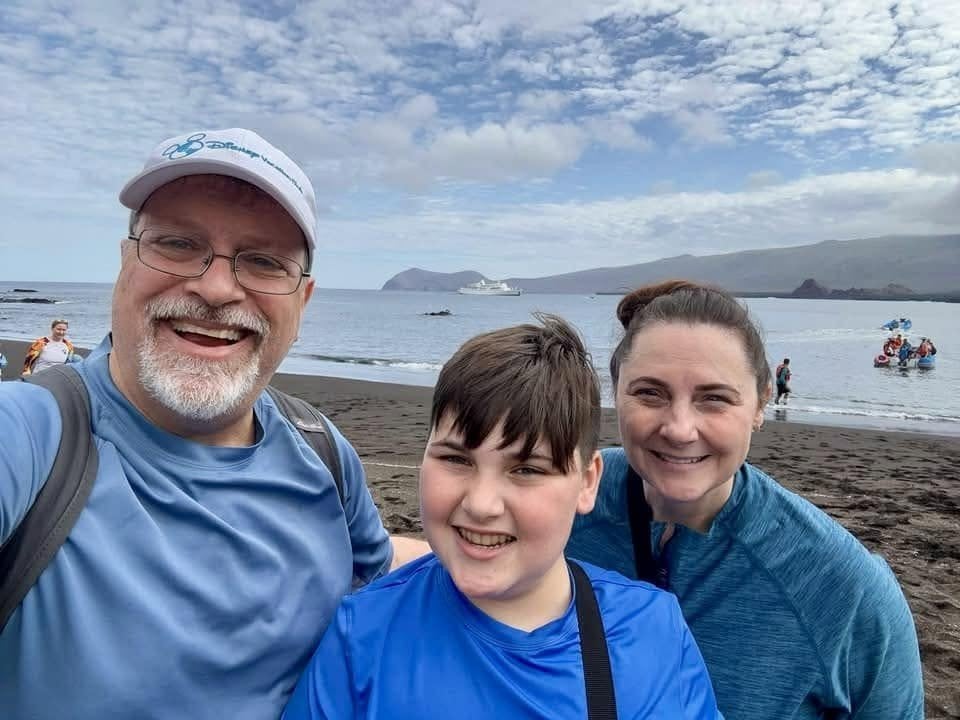 The Herring family smiling on the black volcanic sand beach at Puerto Egas Santiago Island