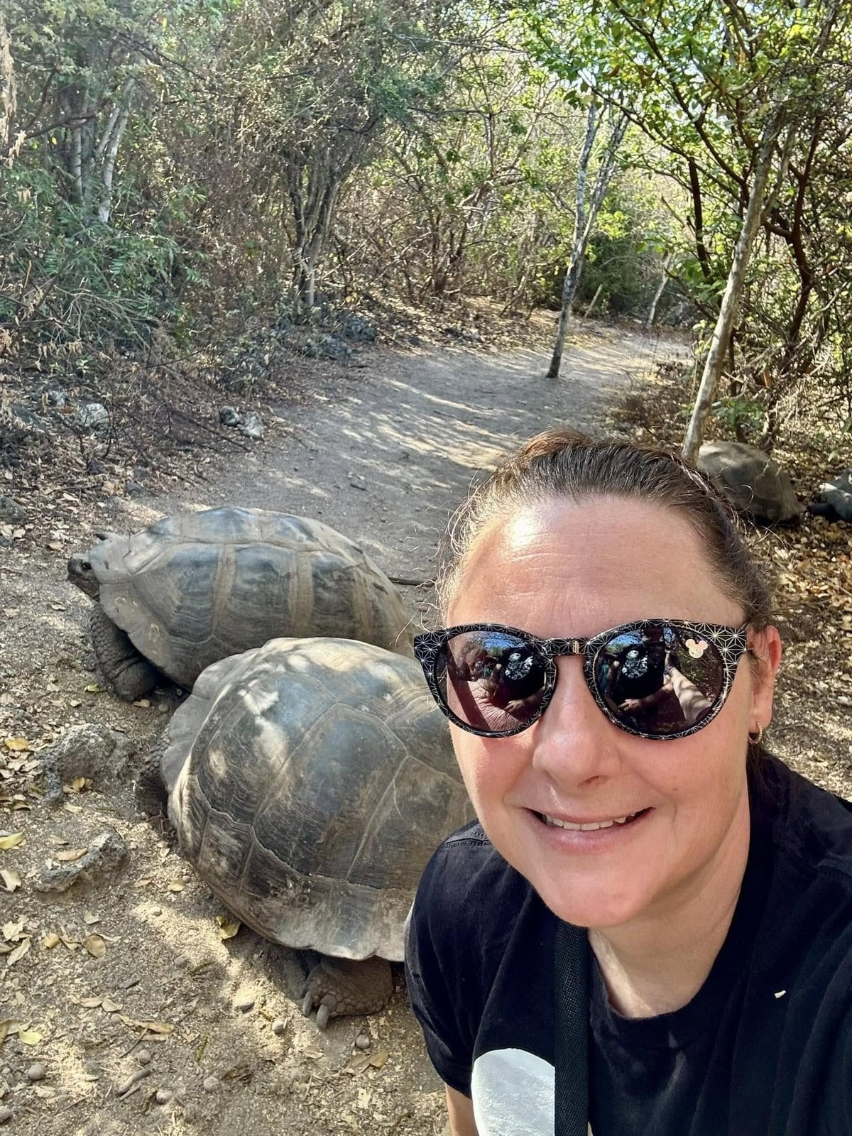 Johnnie Herring taking a selfie with two wild Giant Galapagos Tortoises on the trail at Urbina Bay