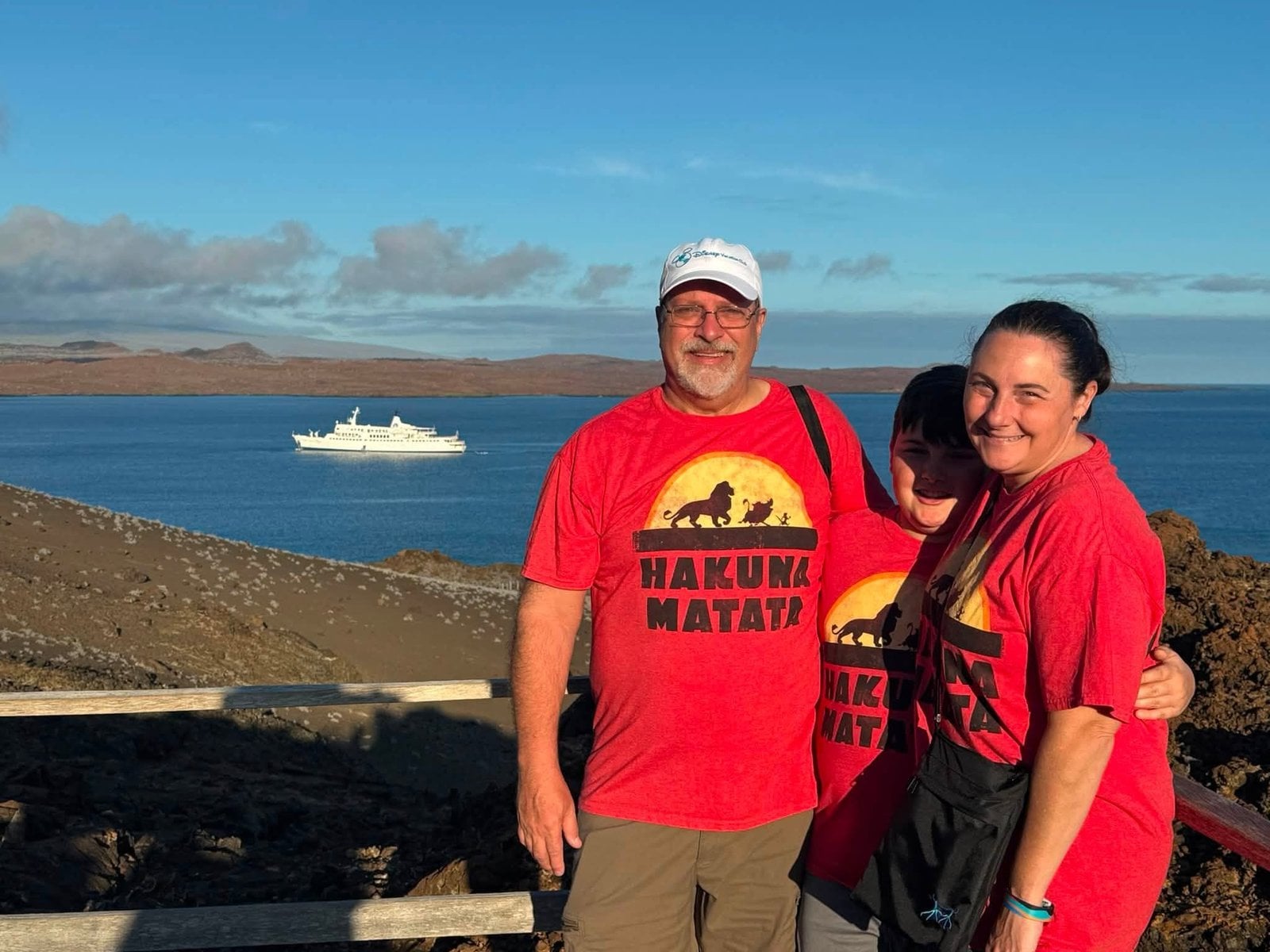 The Herring family in matching Lion King Hakuna Matata shirts overlooking the MV Galapagos Legend expedition ship
