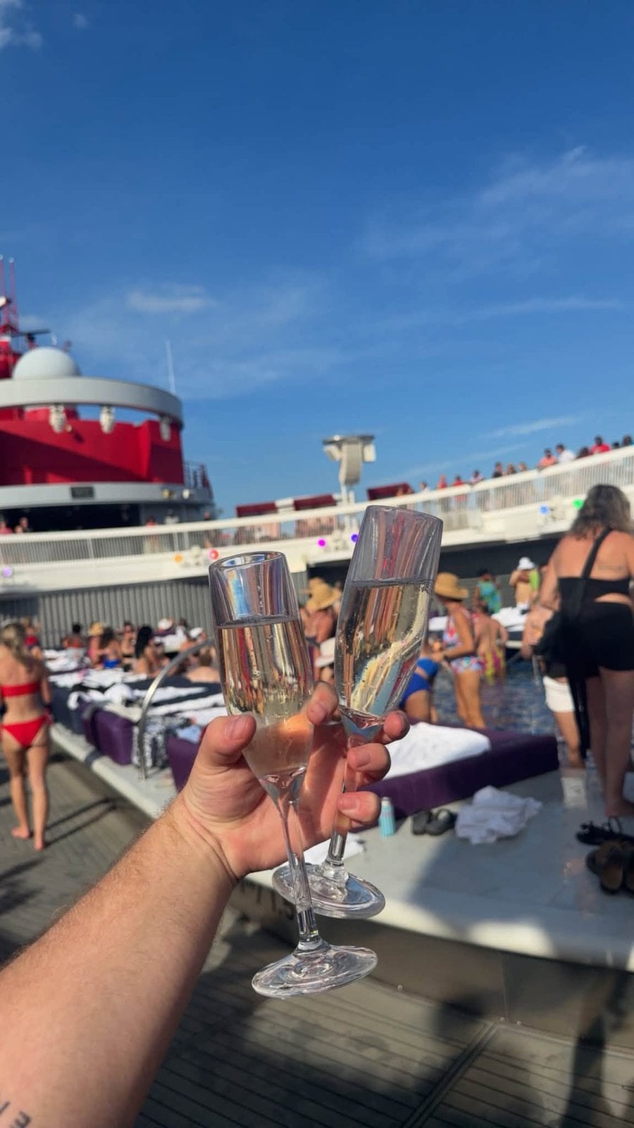 Raising a glass of bubbly poolside under sunny skies aboard Scarlet Lady