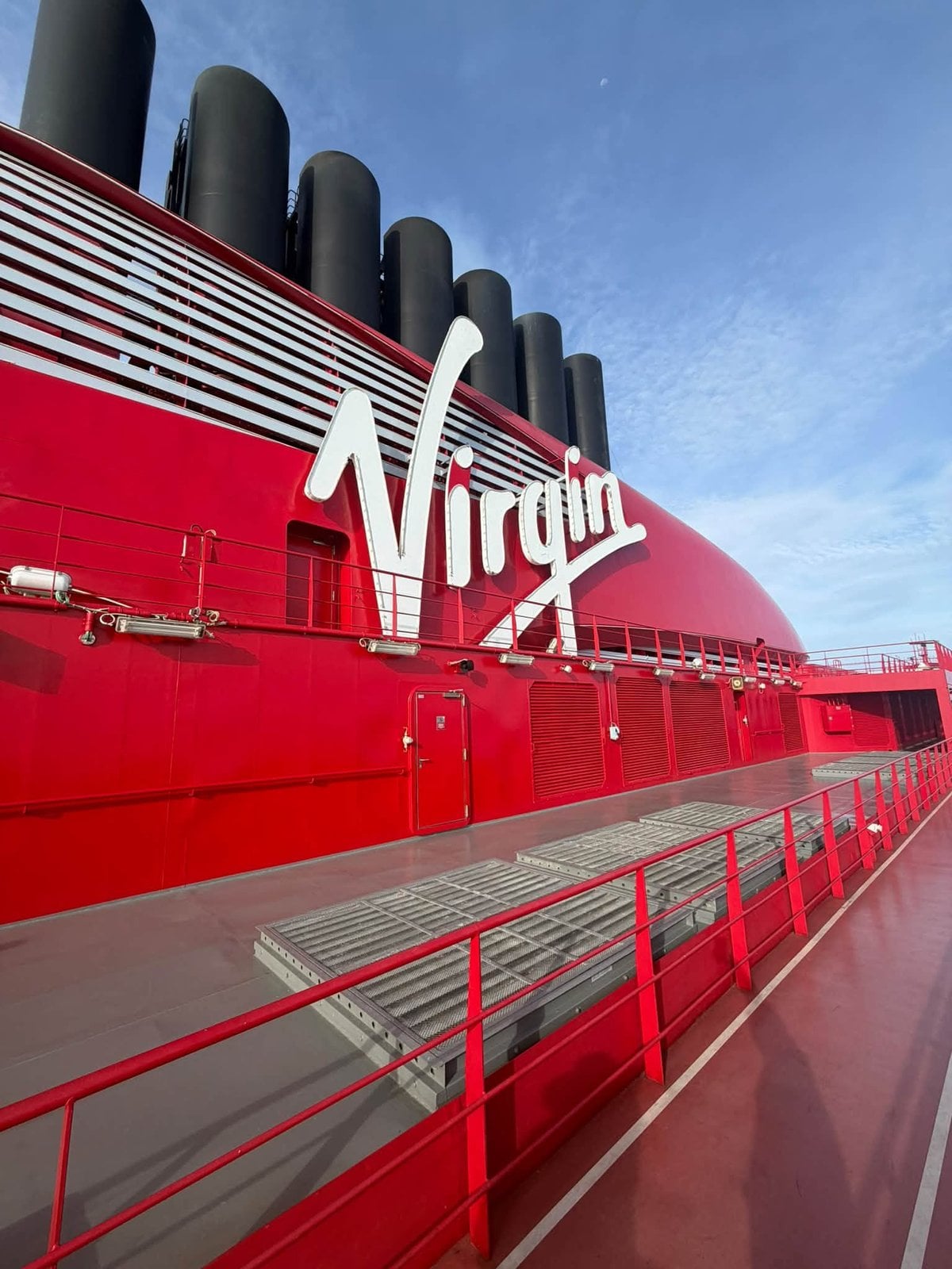 Close-up of the iconic red Virgin Voyages funnel against a bright blue sky