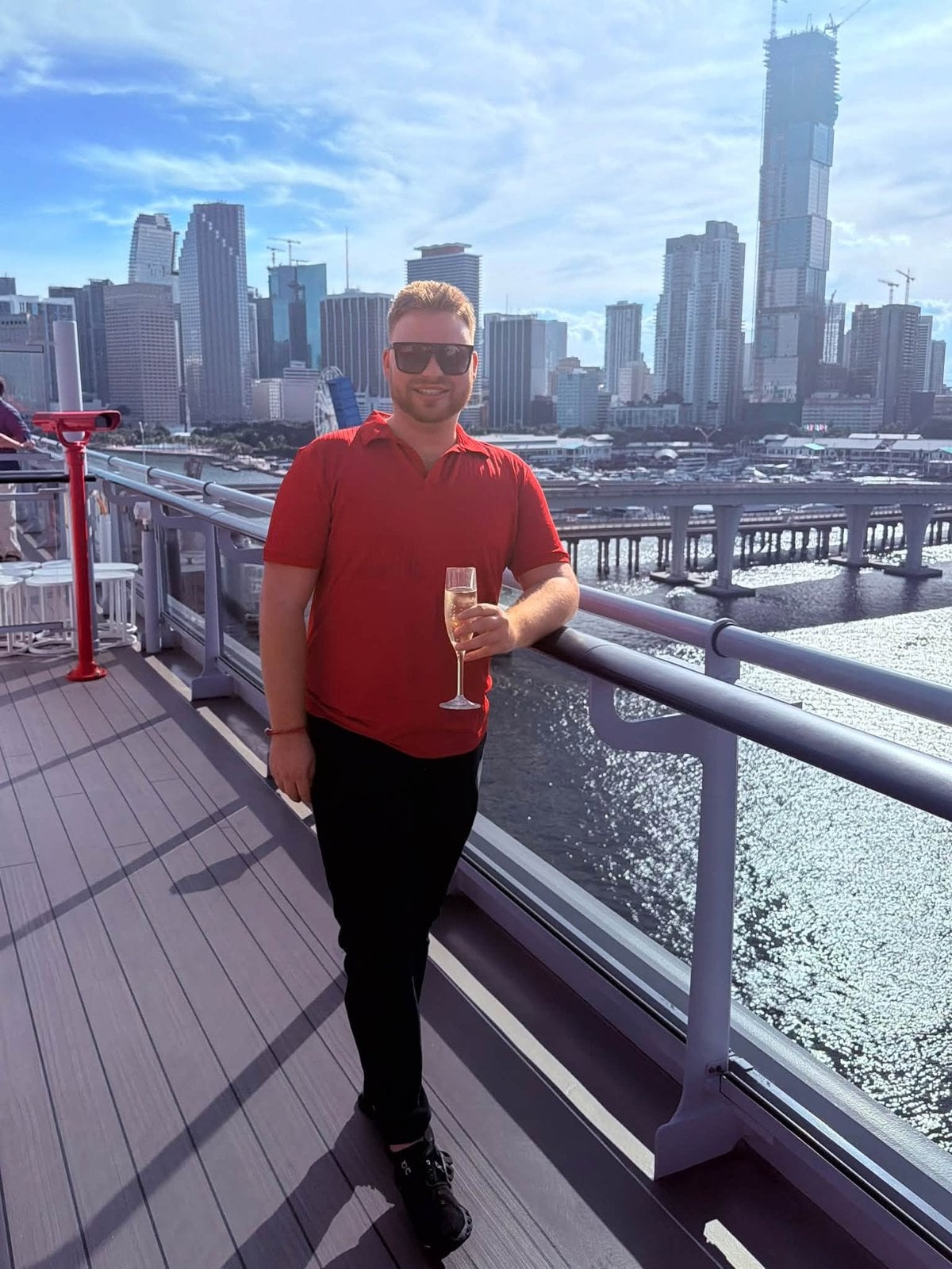 Logan White enjoying a glass of champagne on deck with the Miami skyline in the background