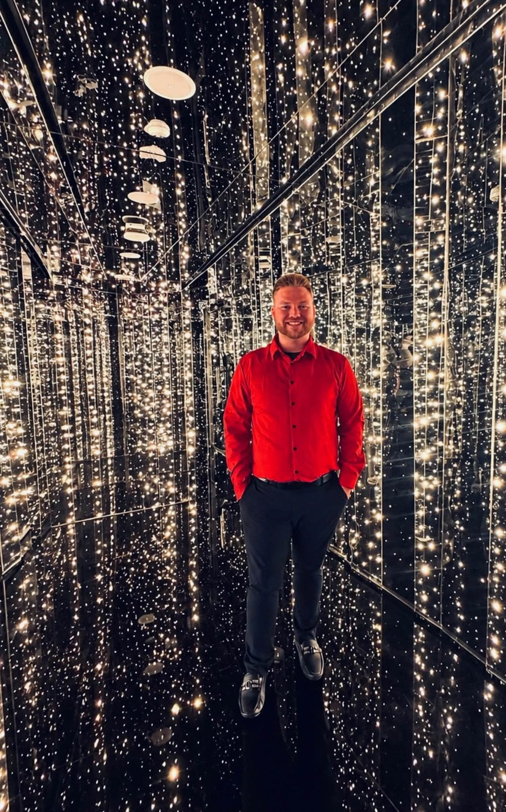 Logan White dressed in red inside The Manor mirror tunnel on Scarlet Night