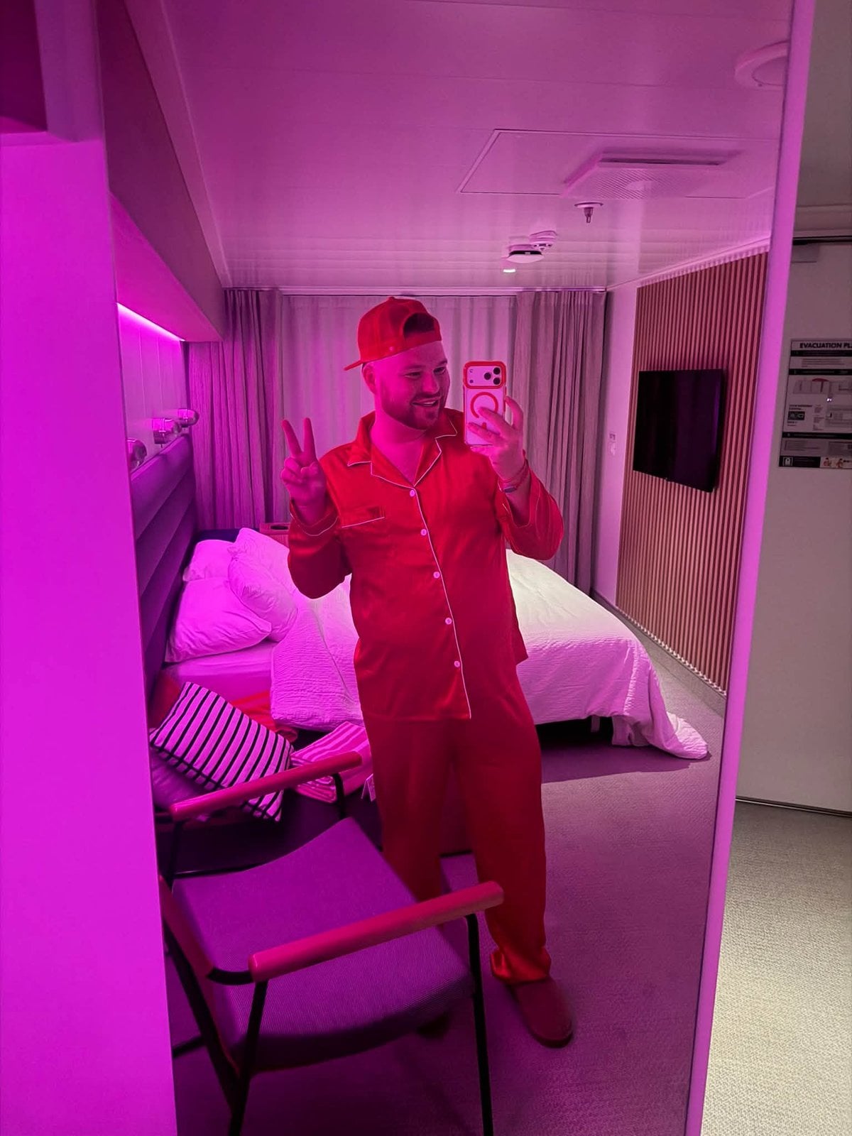 Logan White in red pajamas with pink mood lighting in his Sea Terrace cabin