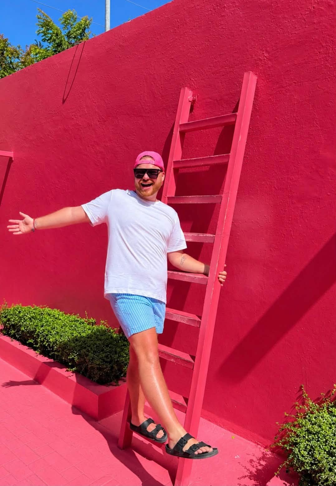 Logan White posing on the iconic pink ladder wall at The Beach Club at Bimini, Bahamas