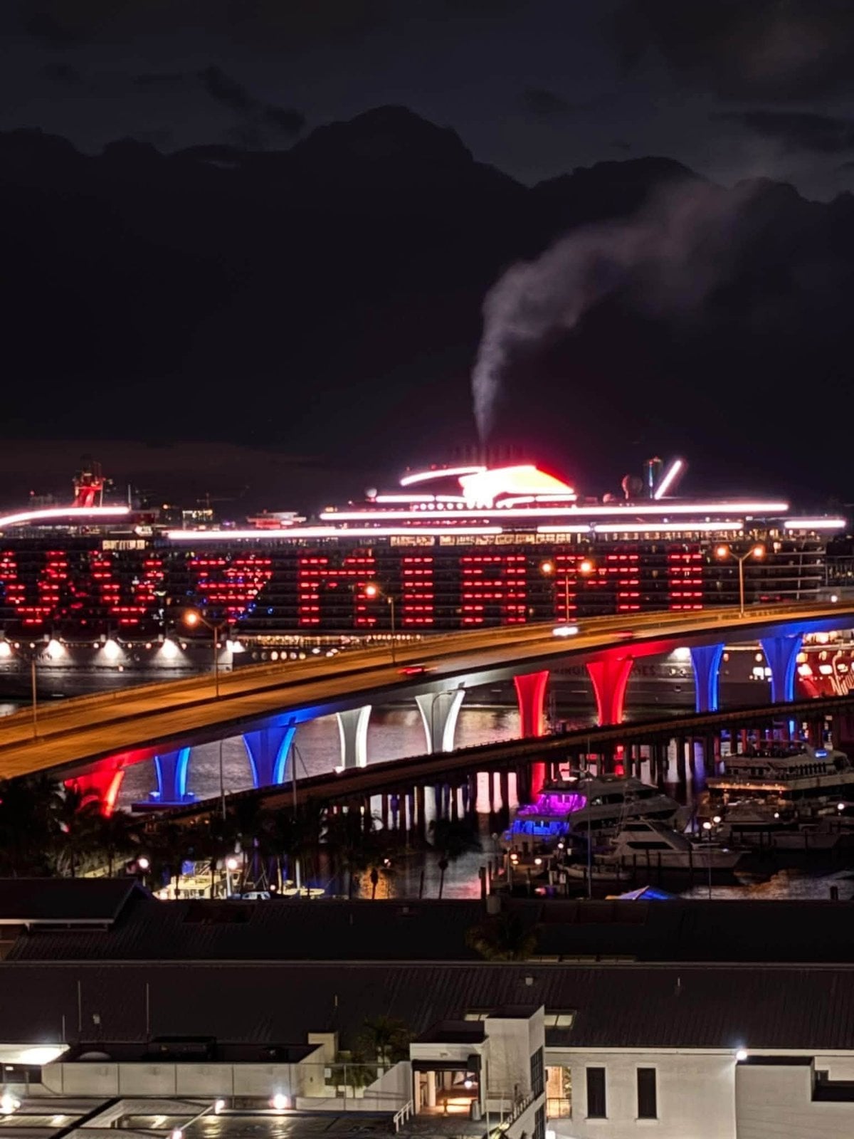 Virgin Voyages' Scarlet Lady glowing in signature red illumination at night