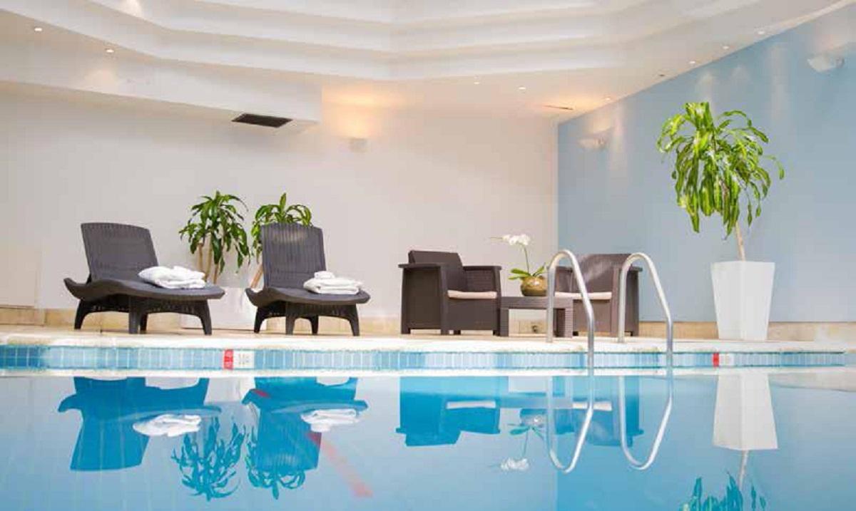 Heated indoor swimming pool beneath glass solarium skylight