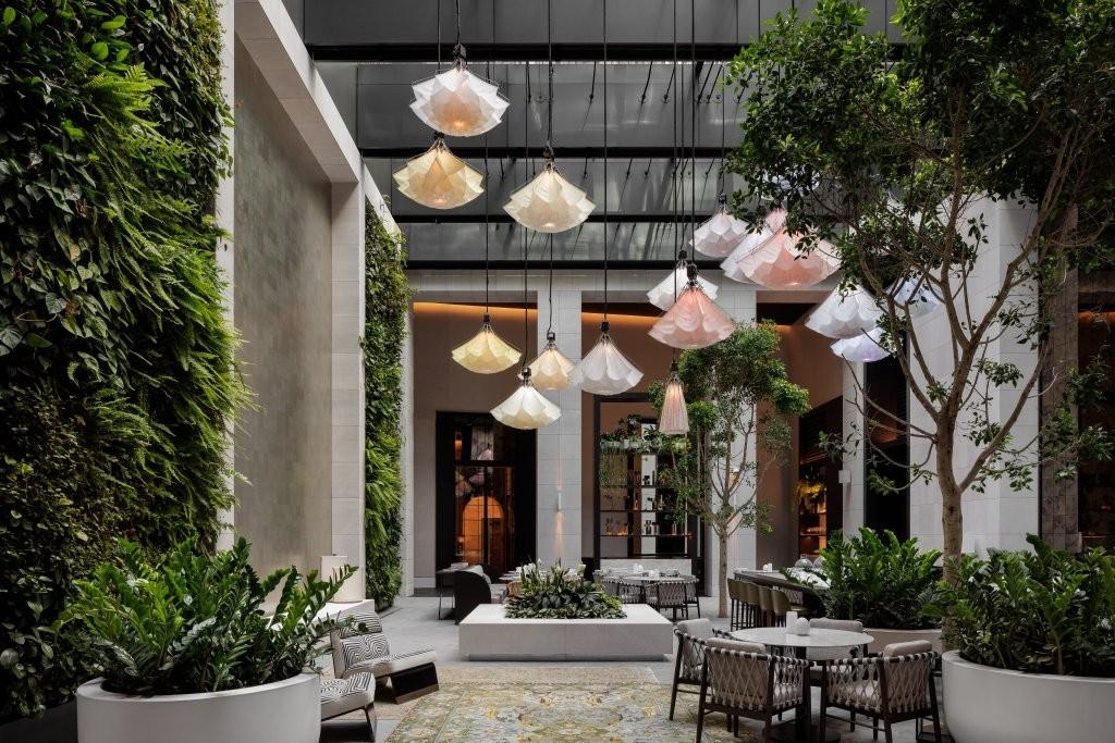 Aperture central ground floor atrium with lush living plant canopy and kinetic light installation