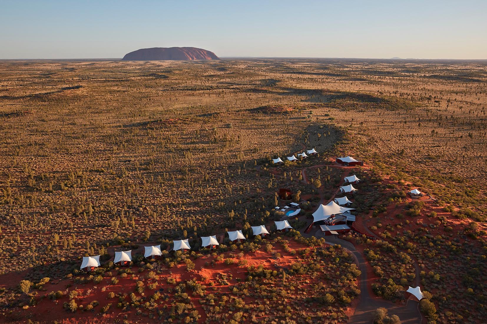 Aerial view of luxury tented pavilions resting on red desert dunes