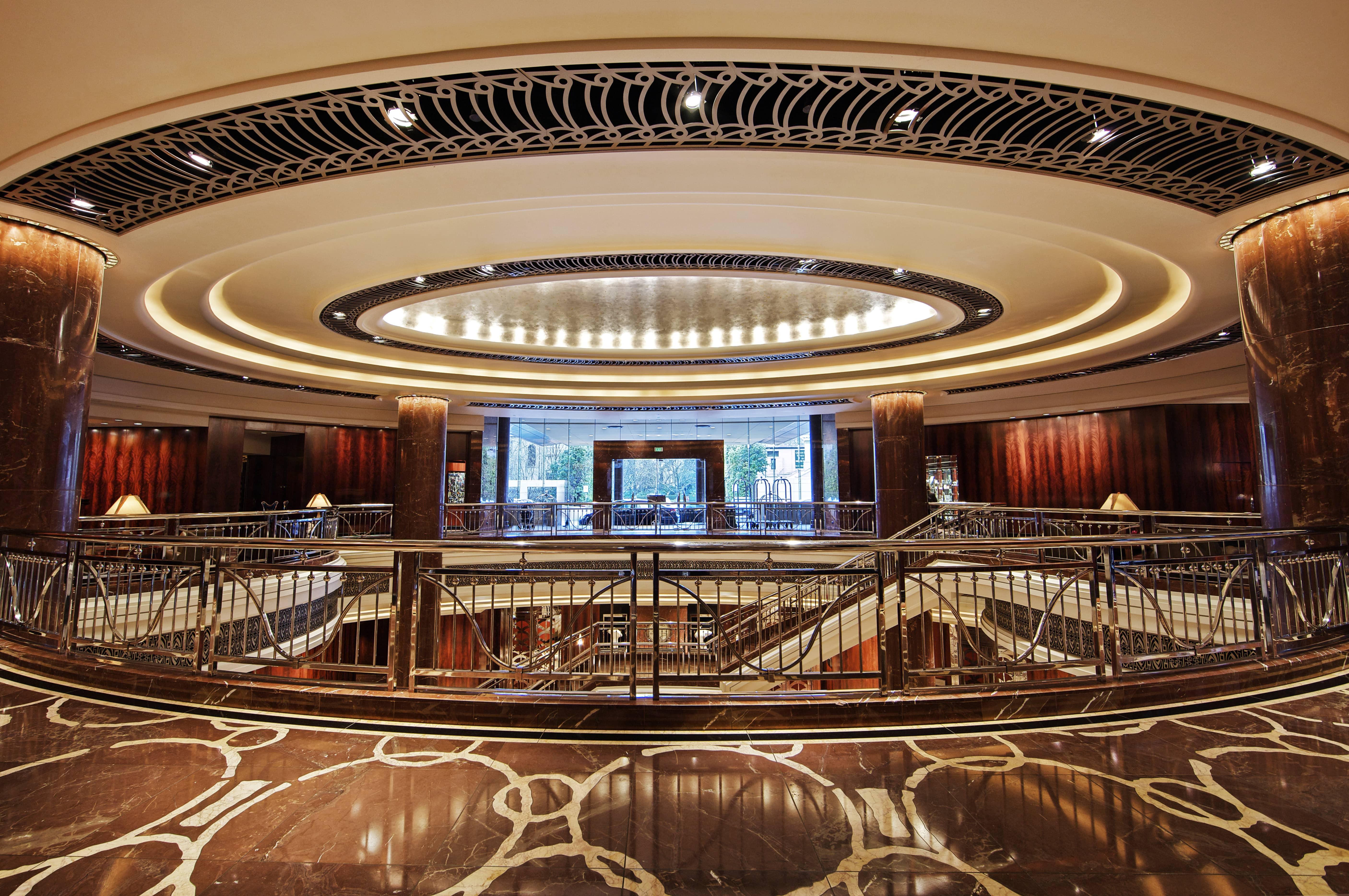 Grand Art Deco inspired lobby lounge with sweeping curved staircase and warm timber paneling