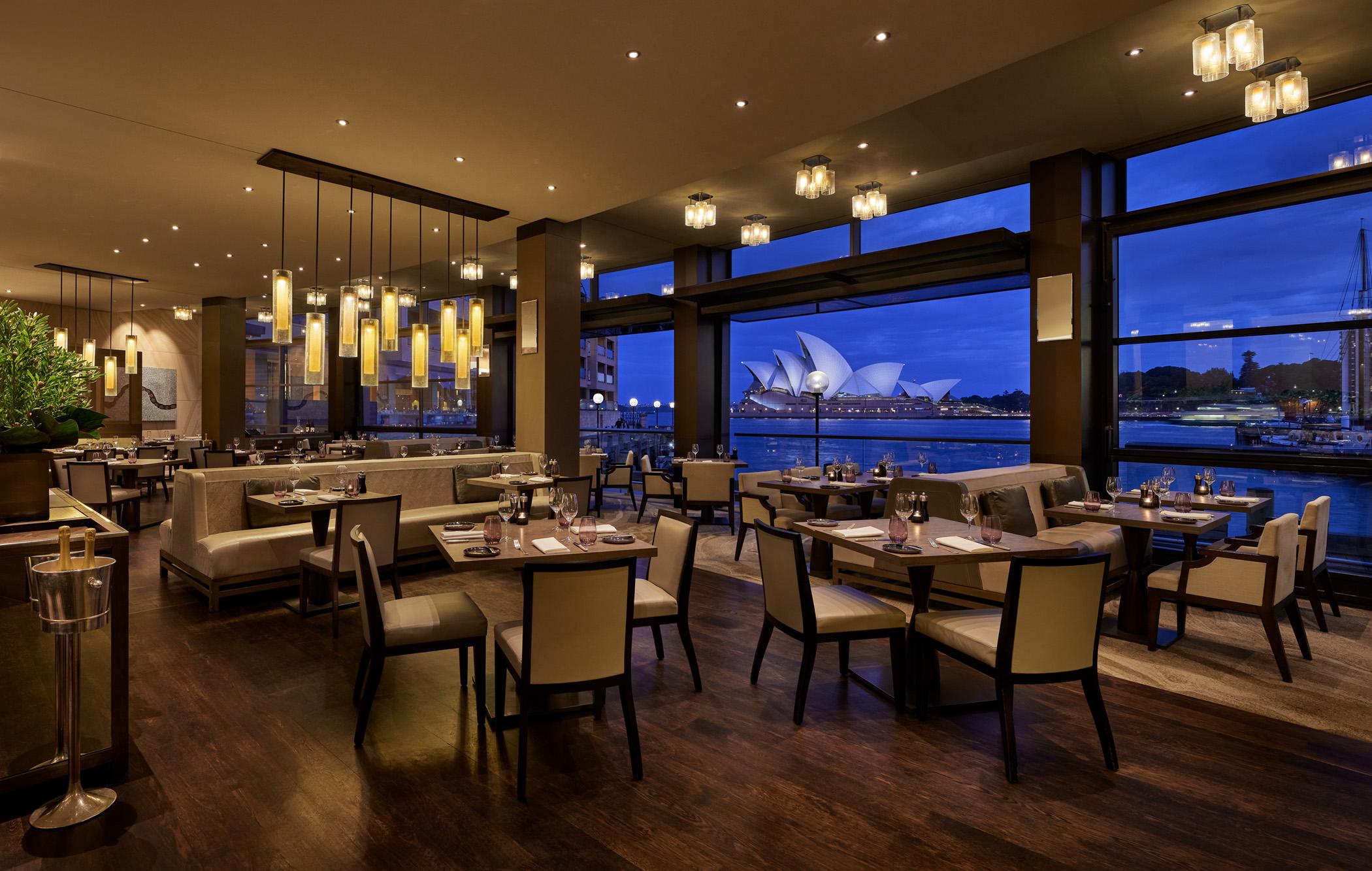 The Dining Room waterfront restaurant framing dusk views of the illuminated Sydney Opera House