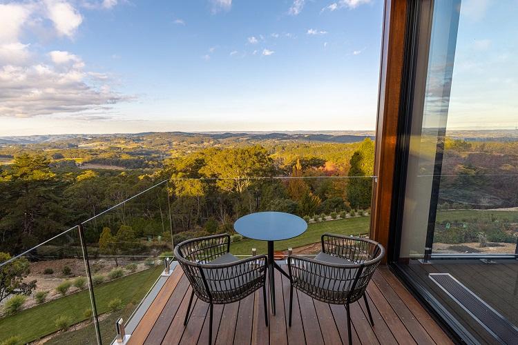 Private furnished suite balcony with oversized daybed framing the Piccadilly Valley vineyards