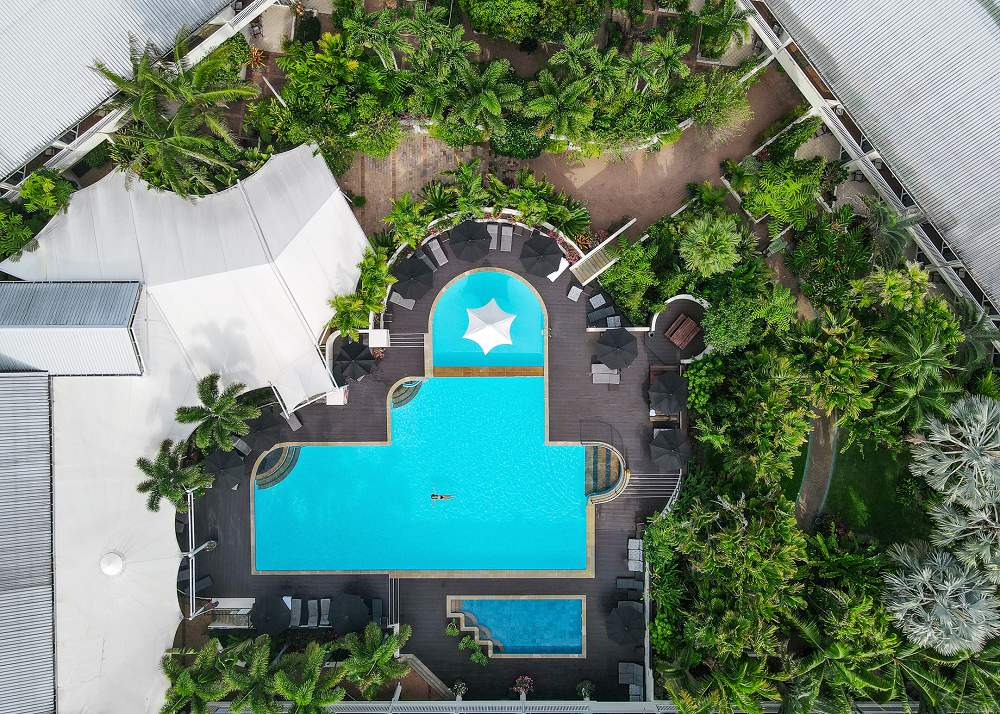 Expansive outdoor resort swimming pool surrounded by palm trees and comfortable sun lounges