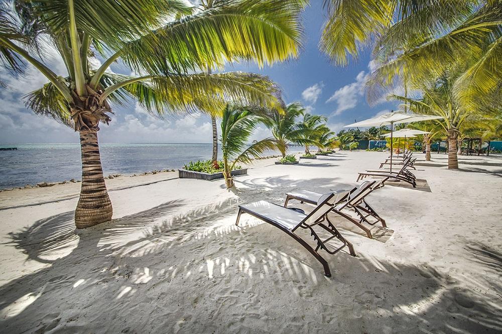 Secluded private white sand beach with thatched palapas and azure sea