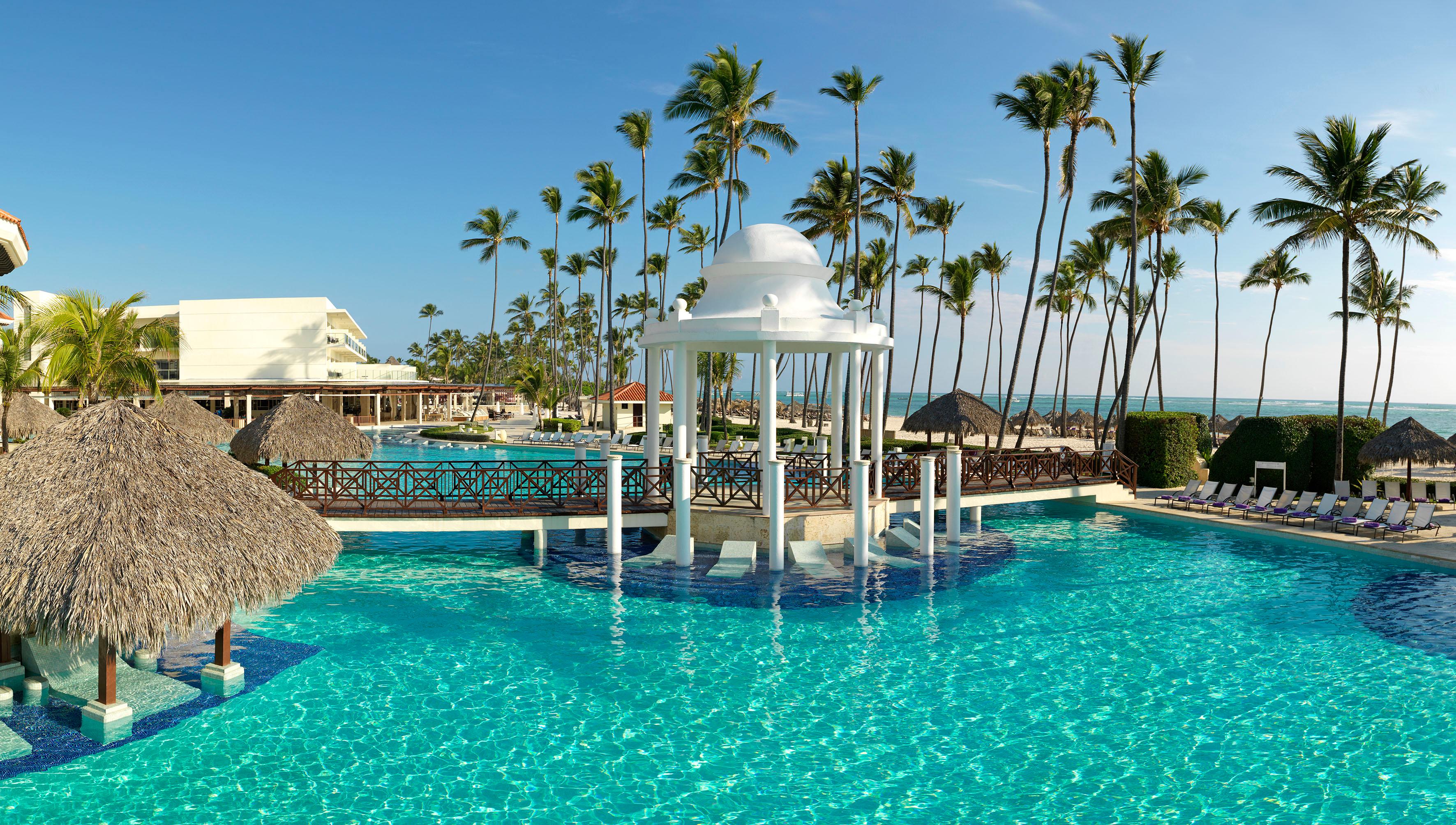Main swimming pool surrounded by tropical palm trees and loungers