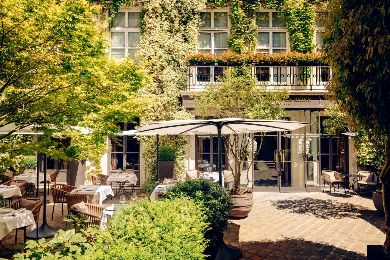 Pavillon de la Reine sunlit cobblestone courtyard terrace and garden loungers